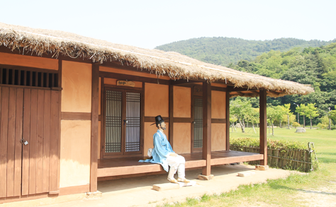 유배지의 초가집을 복원한 모습. 마루 위에 한 선비가 앉아 멍하니 허공을 응시하고 있다.