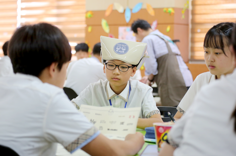 한 학생이 자신의 발표물을 다른 두 명의 친구들에게 설명하고 있다.