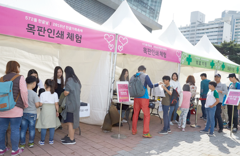 목판인쇄체험 부스 전경. 10여 명의 관람객이 부스에서 목판인쇄 체험을 진행하고 있다.