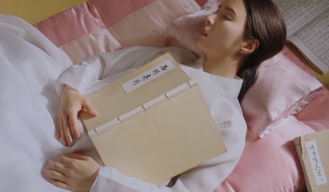 배우 신세경이 하얀 한복을 입고 누워 팔위에 책을 펼쳐놓은 채 잠을 청하고 있다.