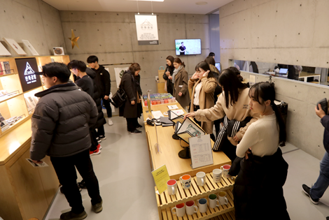 14명의 젊은 남녀가 판화 체험을 할 수 있는 있는 공간에서 각자 무슨 체험을 할 지 살펴보고 있다.
