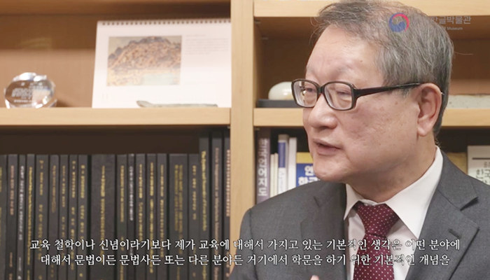 책장을 배경으로 자리에 앉아 이야기하는 권재일 한글학회장. 
“교육 철학이나 신념이라기보다 제가 교육에 대해 가지고 있는 기본적인 생각은 어떤 분야에 대해서 문법이든 문법사든 또는 다른 분야든 거기에서 학문을 하기 위한 기본적인 개념을”