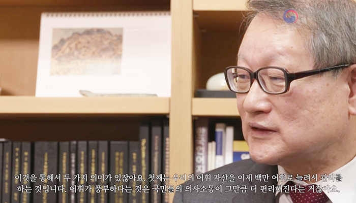 책장을 배경으로 자리에 앉아 이야기하는 권재일 한글학회장. 
“이것을 통해서 두 가지 의미가 있잖아요. 첫째는 우리의 어휘 자산을 이제 백만 어휘로 늘려서 관리를 하는 것입니다. 어휘가 풍부하다는 것은 국민들의 의사소통이 그만큼 더 편리해진다는 거잖아요.”