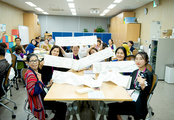 20여 명의 외국인 프로그램 체험자들이 자신이 그린 한글 서예 작품을 들어 카메라를 향해 보여주고 있다.