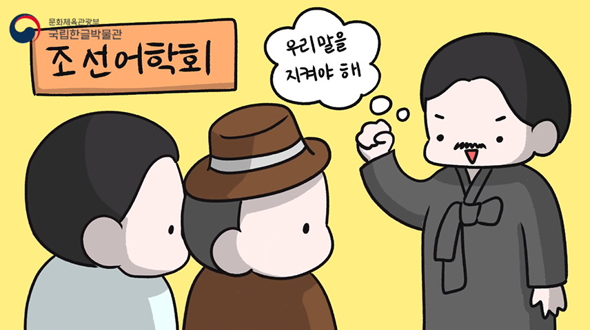 ‘조선어학회’란 팻말이 걸린 곳에 한글학자로 보이는 캐릭터가 “우리말을 지켜야 해”라고 오른팔을 들고 강하게 웅변하고 있다. 좌측으로 갈색 모자를 쓴 캐릭터와 흰 옷을 입은 캐릭터가 경청하고 있다.