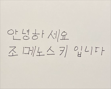조 메노키스가 적어서 보내온 한국말 인사. 종이 위에 ‘안녕하세요 조 메노스키입니다’ 라고 적혀있다.