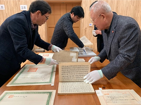 한국학중앙연구원의 장서각을 찾은 박재갑 교수의 모습. 박재갑 교수를 비롯해 네 명의 인물이 손에 라텍스 장갑을 착용한 채 고서를 넘겨보고 있다. 