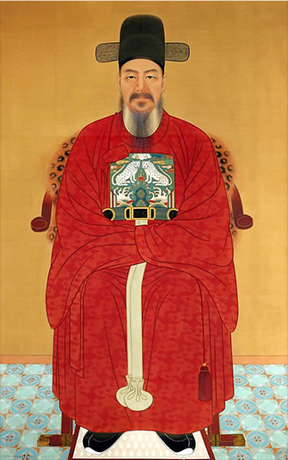 이순신 장군의 초상화. 수염을 기른 이순신 장군이 검은색 사모를 쓰고 붉은색 관복을 입은 채 의자에 앉아 있다.