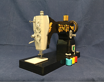 블록 창작가 진형준 작가의 블록 작품. 블록으로 만든 재봉틀. 검은색 몸체에 황금색 무늬가 들어가 있다. 바늘 부분은 상아빛 블록으로 제작됐다. 블록으로 만든 하늘색, 노란색, 빨간색의 실타래도 재봉틀 옆에 놓여 있다.