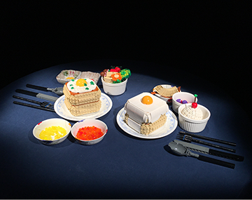진형준 작가가 블록으로 만든 음식. 접시 위에는 블록으로 만든 팬케이크와 소스, 샐러드와 디저트가 놓여 있다. 숟가락, 나이프, 포크 두 쌍이 마주 보고 놓여 있다. 