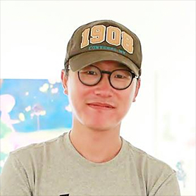 김현 작가의 사진. ‘1908’이 적혀있는 갈색 모자를 쓰고 검은색 뿔테 안경을 썼다. 회색빛이 도는 티셔츠를 입은 채 살짝 미소짓고 있다. 