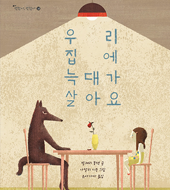 도서 『우리 집에 늑대가 살아요』의 표지. 전등이 하나 켜져 있는 실내에 식탁이 놓여있다. 식탁을 두고 왼쪽과 오른쪽에는 각각 갈색 늑대와 어린 여자아이가 마주 보고 앉아있다. 갈색 늑대는 눈초리가 매우 사납다. 여자아이는 긴 갈색 머리에 노란색 원피스를 입고 있다. 식탁 위에는 노란 화병에 시든 장미꽃 하나가 꽂혀있다.