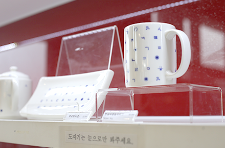 문화상품점에 진열된 한글 도자기이다. 하얀색 머그잔과 접시에 푸른색의 한글 자음이 그려져 있다.