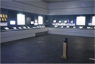 푸른 빛이 도는 전시장 벽면에 한글과 관련된 유물들이 나란히 전시되어 있다. 전시 유물과 더불어 유물을 설명하는 태블릿 pc와 패널이 설치되어 있다.