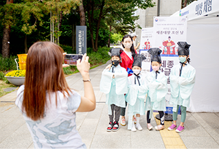 조선 시대 유생의 복장을 한 어린이들과 여성이 나란히 모여있다. 모두 마스크를 착용하고 있다. 한 여성이 핸드폰으로 어린이들의 사진을 찍어주고 있다.  