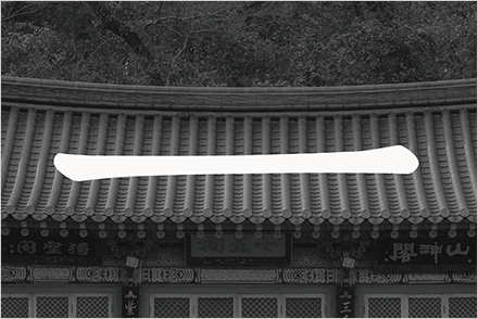 한국 전통식 건물의 기와지붕 위에 모음 으가 적혀있다. 사진은 흑백이며 ‘으’는 흰색으로 처리됐다.