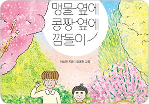 도서 『맹물 옆에 콩짱 옆에 깜돌이』의 표지. 벚꽃과 수많은 꽃들이 흐드러지게 핀 거리에 두 명의 아이가 나란히 서 있다. 왼쪽의 아이는 키가 크고 갈색 머리에 노란 티셔츠를 입었다. 오른쪽 아이는 작은 키에 진한 눈썹을 가지고 있으며 노란색 줄무늬 티셔츠를 입었다.