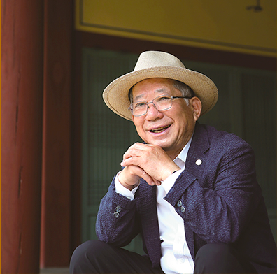 남색 정장과 흰 셔츠를 입은 나태주 시인이 양 무릎에 팔을 올려 두 손을 모아 턱을 괴고 비스듬히 앉아 정면을 응시하고 있다. 안경과 모자를 쓴 나태주 시인은 환하게 웃고 있다.