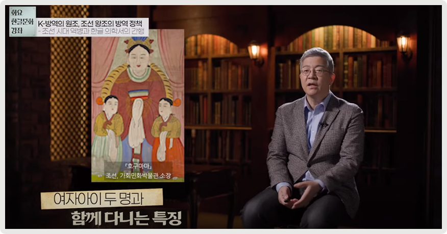 오른쪽에 김호 교수가 앉아서 이야기하고 있다. 왼쪽엔 한 성인 여자가 양옆에 여자아이 둘을 데리고 있는 「호구마마」 그림 사진이 있고, 아래엔 ‘여자아이 두 명과 함께 다니는 특징’이라고 적혀있다.
