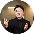 검은색 정장을 입고 안경을 쓴 김동호 수어 통역사가 양손을 들고 왼쪽을 바라보고 있다.