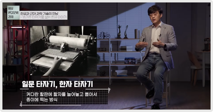김태호 교수가 의자에 앉아 양손을 가운데로 모으며 이야기하고 있다. 그의 왼쪽엔 일문 타자기, 한자 타자기의 흑백 사진이 있으며, 그 밑엔 ‘커다란 활판에 활자를 늘어놓고 뽑아서 종이에 찍는 방식’이라는 설명이 적혀있다.
