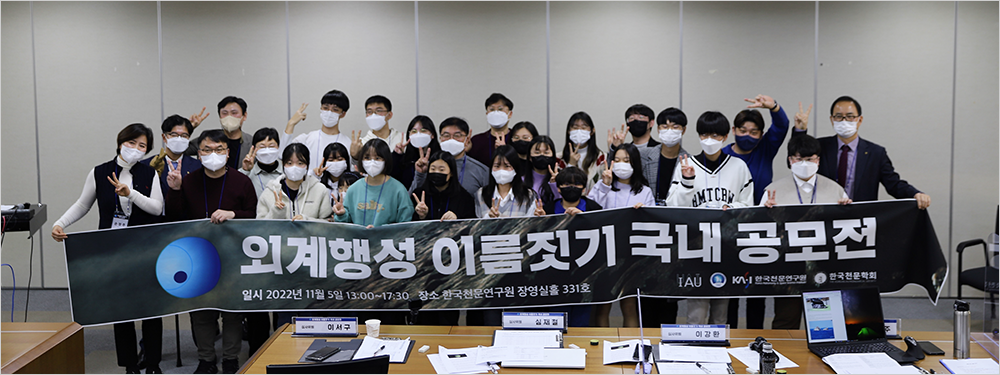 2022년 11월 열린 ‘외계행성 이름 짓기 국내 공모전’ 참가자들 단체 사진이다. 많은 사람이 검은색 ‘외계행성 이름짓기 국내 공모전’이라는 현수막을 단체로 들고 정면을 바라보고 있다.