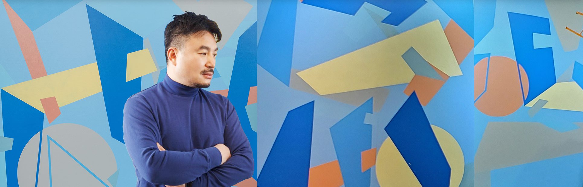 남색 옷을 입은 금보성 작가가 팔짱을 끼고 오른쪽 아래를 향해 바라보고 있다. 뒤에는 파랑, 주황, 노랑, 회색 등으로 한글 자음과 도형들이 곳곳에 그려져 있다.
