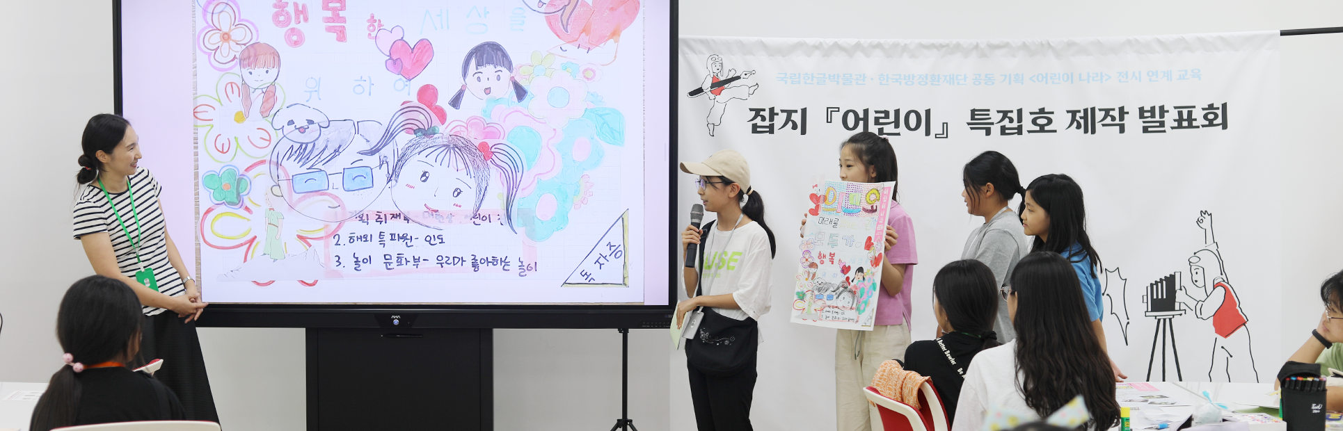 기획 전시 <어린이 나라>와 연계하여 국립한글박물관과 한국방정환재단이 공동으로 기획한 ‘잡지 『어린이』 특집호 만들기’ 현장 사진이다. 마이크를 든 한 여자 어린이가 화면을 띄워놓고 무언가를 발표하고 있다. 화면 속엔 어린이 형상의 얼굴 그림이 여러 개 그려져 있다. 