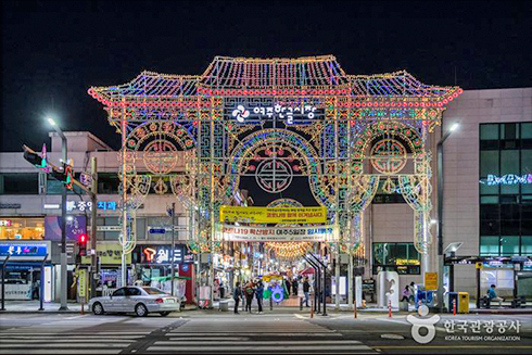 여주한글시장 입구 사진이다. 시장 입구에 화려한 불빛으로 꾸며진 옛 기와집 형상이 있다.