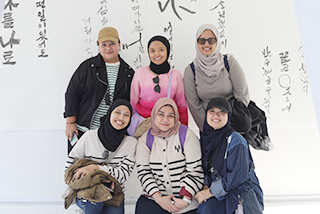 2023년 한글날 기간 국립한글박물관 전경 사진이다. 외국인 여성 6명이 전시물 앞에서 카메라를 향해 포즈를 취하고 있다.