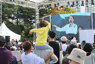 2023년 한글날 기간 국립한글박물관 전경 사진이다. 사람들이 앞에서 펼쳐지고 있는 공연을 보고 있는 뒷모습이다. 