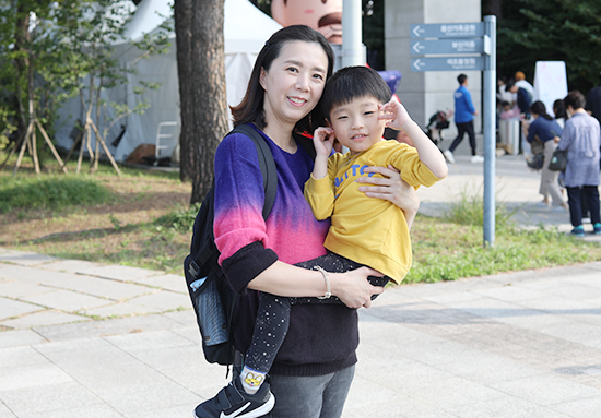 2023년 한글날 국립한글박물관을 찾은 관람객 미니 인터뷰 사진이다. 한 어머니가 남자아이를 안고 카메라를 향해 포즈를 취하고 있다.