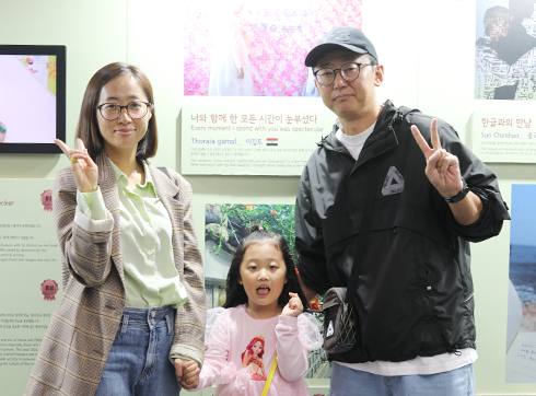 2023년 한글날 이촌역 ‘박물관 나들길’ <2023 내가 만난 한글 사진·영상 공모전> 및 <제9회 책 속 인물에게 보내는 한글 손 편지 공모전> 수상작 전시 현장 사진이다. 부부와 여자 어린이가 수상작 앞에서 카메라를 향해 포즈를 취하고 있다.