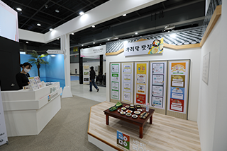 <2023 한글문화산업전시회>의 ‘한글 산업의 장’ 현장 사진이다. ‘우리말 맛집’ 전시관이 있는데, 갈색 상에 여러 가지 음식들이 올라가 있다.