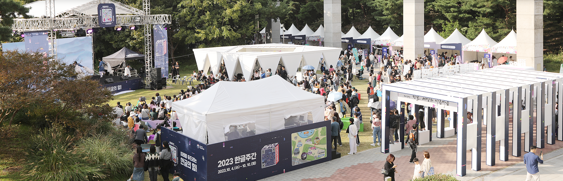 2023년 한글날 국립한글박물관 전경 사진이다. ‘2023 한글주간’ 행사가 펼쳐지고 있다. 정면엔 큰 부스가 설치돼 있으며, 들판 위에 설치된 무대에선 공연이 진행 중이다. 사람들이 빼곡하게 앉거나 서 공연을 보고 있으며, 오른쪽 옆엔 작은 부스들이 설치돼 있다.