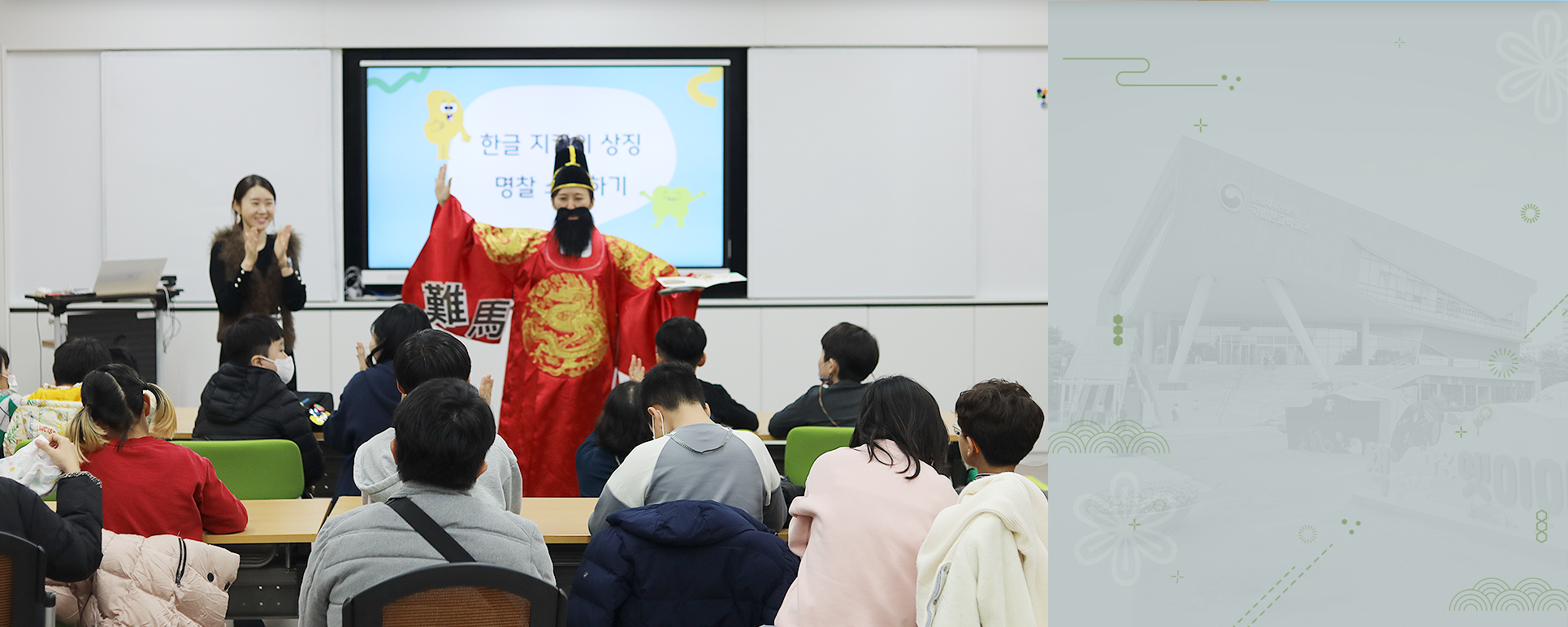 박물관은 지금 기사 사진. 특수학급 학생들을 대상으로 한 한글문화 체험 교육 <세종의 친구, 한글 지킴이>의 시범 현장 사진이다. 임금님 복장을 한 강사가 왼손에 책을 들고 오른손은 옆으로 뻗으며 학생들을 가르치고 있고, 왼쪽엔 한 여성이 손뼉을 치고 있다.