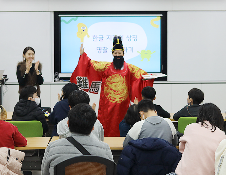 박물관은 지금 기사 사진. 특수학급 학생들을 대상으로 한 한글문화 체험 교육 <세종의 친구, 한글 지킴이>의 시범 현장 사진이다. 임금님 복장을 한 강사가 왼손에 책을 들고 오른손은 옆으로 뻗으며 학생들을 가르치고 있고, 왼쪽엔 한 여성이 손뼉을 치고 있다.
