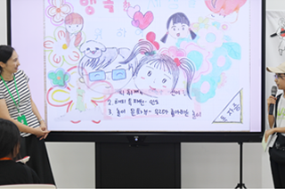 기획 전시 <어린이 나라>와 연계하여 국립한글박물관과 한국방정환재단이 공동으로 기획한 ‘잡지 『어린이』 특집호 만들기’ 현장 사진이다. 마이크를 든 한 여자 어린이가 화면을 띄워놓고 무언가를 발표하고 있다. 화면 속엔 어린이 형상의 얼굴 그림이 여러 개 그려져 있다. 