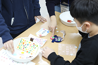 특수학급 학생들을 대상으로 한 한글문화 체험 교육 <세종의 친구, 한글 지킴이>의 시범 현장 사진이다. 한 어린이가 스티커를 이용해 이름표를 만들고 있다.