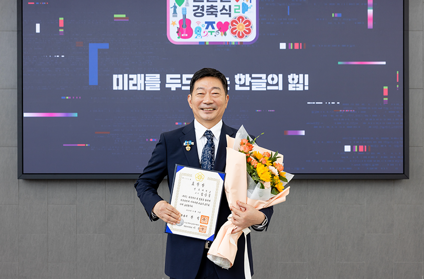 지난해 한글날 경축식에서 한글 유공자로 선정된 김중섭 교수가 오른손엔 표창장, 왼손엔 꽃다발을 들고 환하게 웃고 있다.