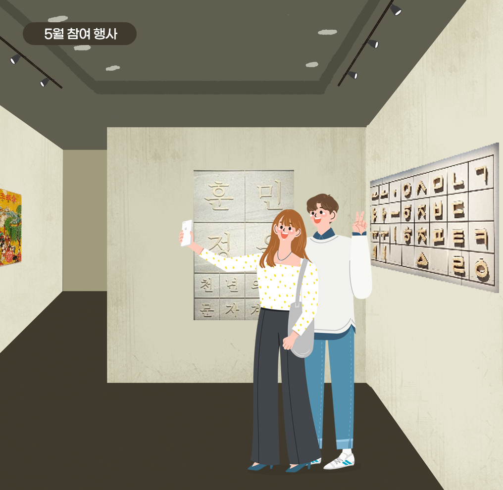 한글박물관 전시장에 남녀가 방문해 전시물을 배경으로 인증샷을 찍고 있다. 긴바지와 노란땡땡이 옷을 입은 여자가 핸드폰을 들고 인증샷을 찍는 모습. 그 뒤에 남자는 환하게 웃으며 손가락으로 V자를 그리고 있다.