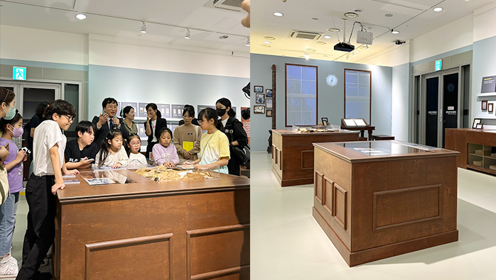 ‘어린이 나라’ 순회전 개막식 행사 현장이다. 두 개의 사진이 하나로 붙어져 있는데, 왼쪽에는 여러 명의 아이와 어른이 나무로 된 전시대 주위에 모여 큐레이터의 설명을 듣고 있는 사진이다. 오른쪽에는 전시 공간의 넓은 전경을 보여주는 사진이 있다. 나무로 만든 테이블이 있는데 관람객들이 서서 작품을 관람할 수 있도록 설치되어 있다. 벽면에는 여러 개의 사진이나 자료가 걸려있다.