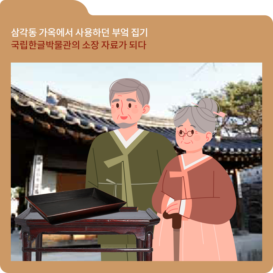 갈색 폴더 그림이 있고, 그림 왼쪽 위에 ‘삼각동 가옥에서 사용하던 부엌 집기 국립한글박물관의 소장 자료가 되다‘라고 적혀 있다. 한옥을 배경으로 사진 중앙에 녹색 한복을 입은 노년의 남성과 다홍색 한복을 입은 노년의 여성이 서 있다. 이들 앞에는 이상억이 기증한 소반과 목반이 놓여 있다.