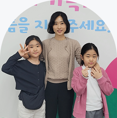 황명자 어머니, 딸 송인영, 송민지 가족사진이다. 맨 오른쪽엔 남색 카디건을 입고 손으로 ‘V’자를 만들고 있는 송인영 양이 있다. 그 옆에는 베이지색 니트와 카디건을 입고 웃고 있는 황명자 씨가 있다. 그녀의 왼쪽에는 분홍색 가디건을 입고 손으로 하트 모양을 만들고 있는 송민지 양이 서 있다.