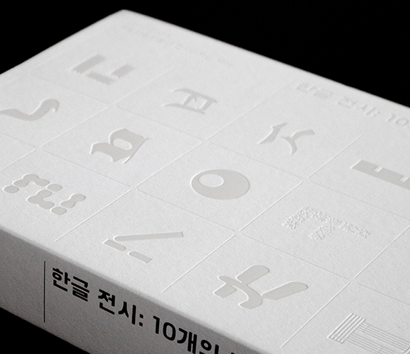 국립한글박물관 10주년 기념 백서 ‘한글 전시: 10개의 질문’ 사진이다. 책 표지는 흰색이고 다양한 한글 자모가 그려져 있다.