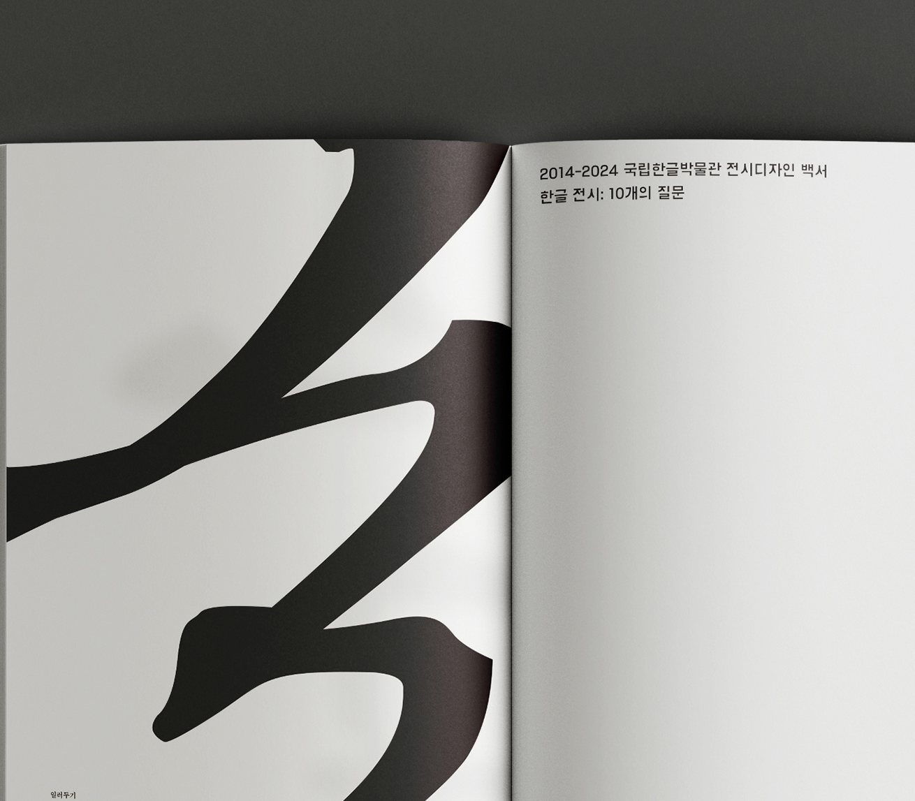 디지털한글박물관 원문 해제 누리집 사진이다. 왼쪽 페이지에는 큼직한 검은색 브러시로 그린 것 같은 그래픽이 그려져 있다. 오른쪽 페이지는 흰색 여백이 대부분을 차지하며, 상단에 간결한 한글 문장이 배치되어 있다.