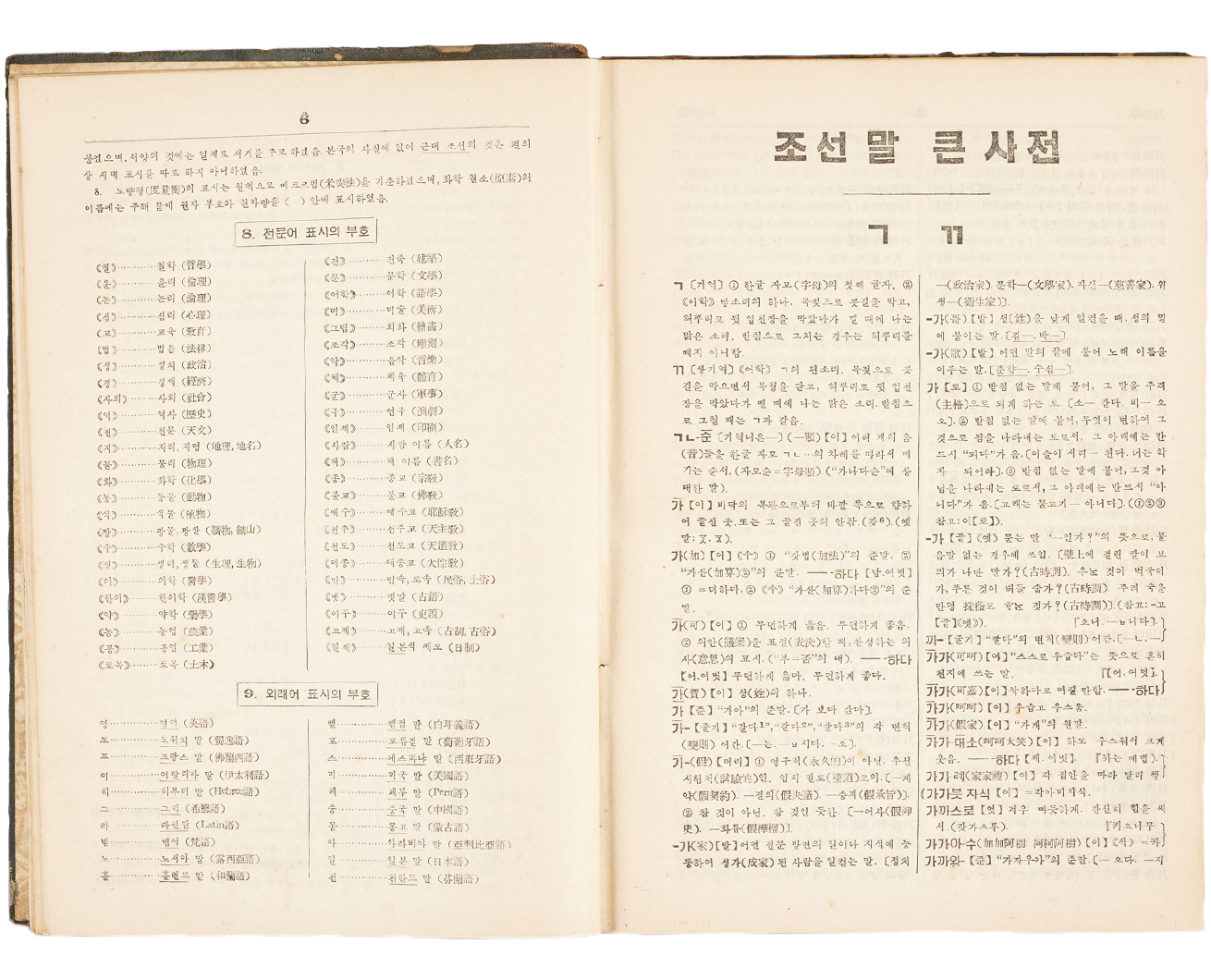 ‘조선말 큰 사전’ 사진이다. 조선말 큰 사전의 한 페이지가 펼쳐져 있다. 왼쪽 페이지에는 전문어 표시의 부호가 적혀 있고, 오른쪽 페이지에는 ‘ㄱ’과 ‘ㄲ’에 해당하는 설명이 적혀 있다.