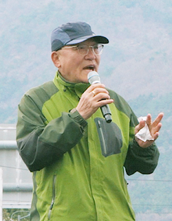 참여 관람객 사진이다. 초록색 바람막이와 회색 모자를 쓴 중년의 남성이 마이크를 들고 말하고 있다.