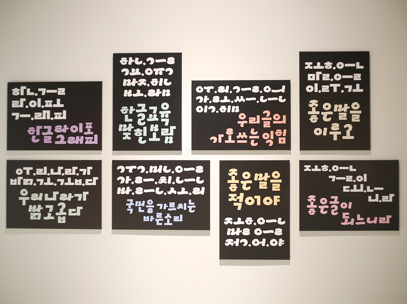 한동훈 ‘말의 형태’ 작품이다. 벽에 검은색 사각 패널이 붙어져 있고, 각 패널에는 자유롭고 실험적인 분위기의 글씨체로 쓰인 여러 문장이 적혀있다. 