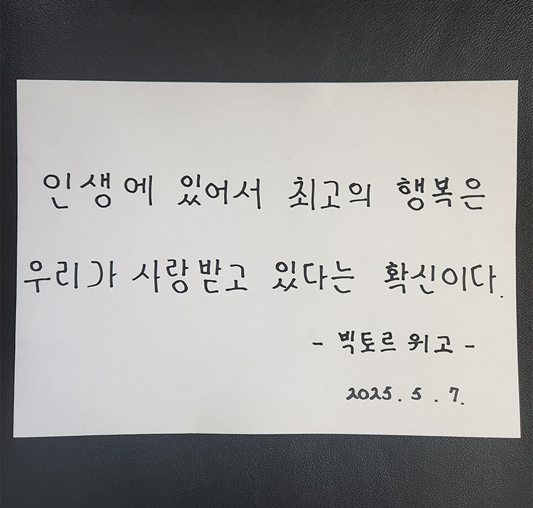 5월 ‘한 글’쓰기 참여작 사진이다. 종이에 검은색 펜으로 다음과 같은 문구가 적혀있다. ‘인생에 있어서 최고의 행복은 우리가 사랑받고 있다는 확신이다.’ 빅토르 위고.